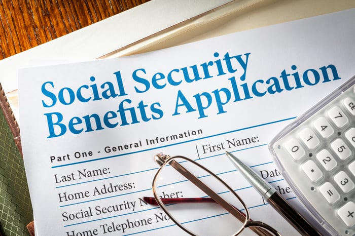 Cup, pen and calculator on the form labeled Applying for Social Security Benefits.