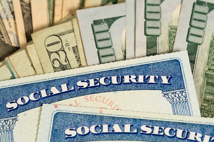 Two social security cards placed on top of a pile of money.